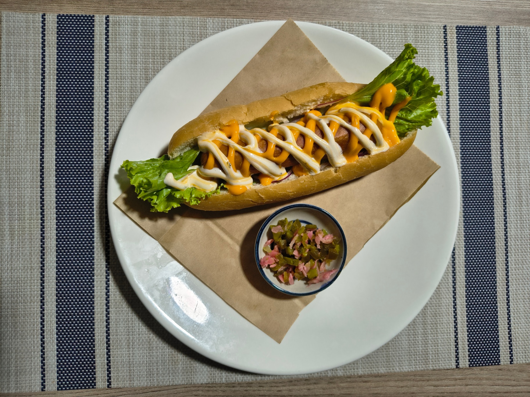 Kwang Kitchen hotdog with cheese sauce, mayo, lettuce and pickles